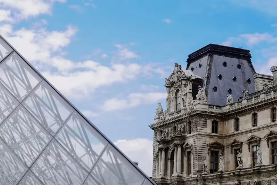 The glass Pyramid of the Louvre beside a sculpted pavilion of the palace