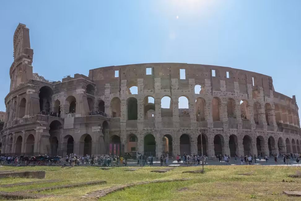 The outer walls of the Colosseum in Rome under a clear sky.