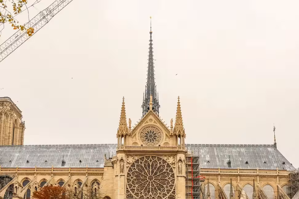 A transept rose window of Notre-Dame de Paris, with the spire above the roof.