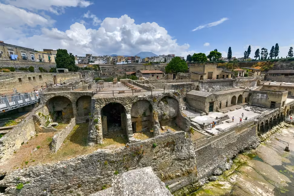 Vaulted arches in the ruins of Herculaneum, with Vesuvius in the distance.