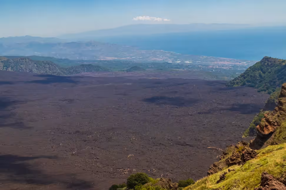 La Valle del Bove, sur l'Etna, couverte de lave noire, avec la mer au loin