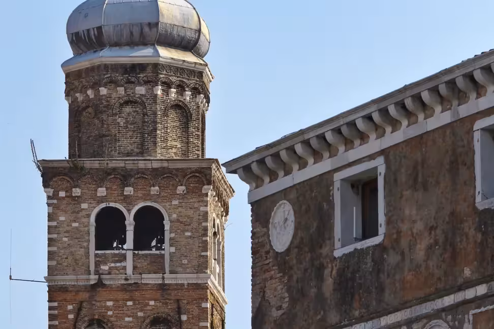 Un ancien clocher en brique à côté de la façade gothique d'un palais à Murano
