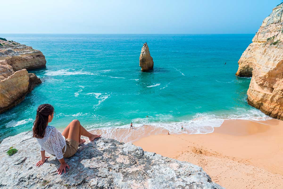 Praia do Carvalho, a secluded Algarve gem accessed through a tunnel carved into the cliffs, offers a unique beach experience with its golden sands, clear waters ideal for snorkeling, and dramatic surrounding rock formations, making it popular for those seeking a more adventurous coastal visit.