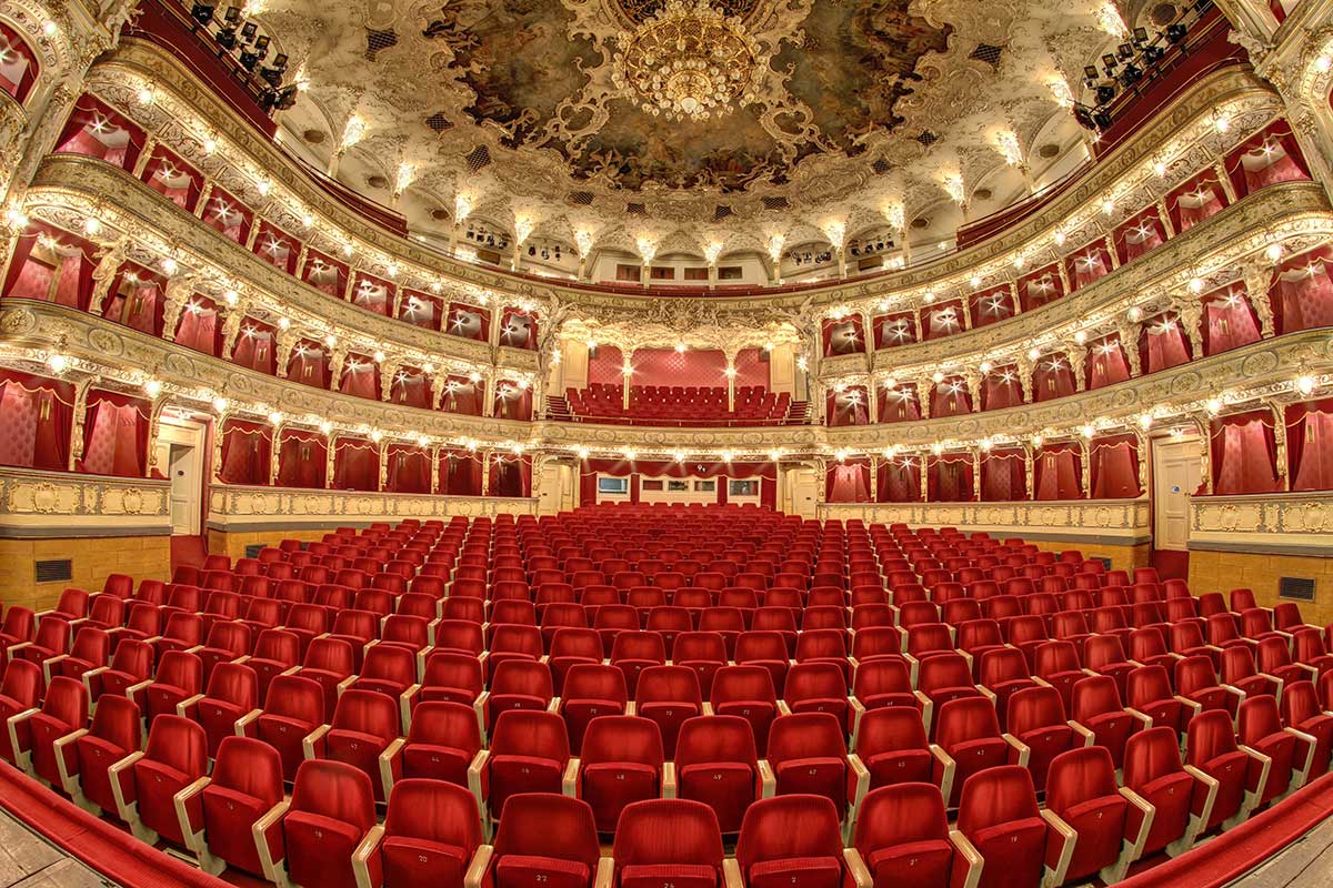 The opulent interior of the Vienna State Opera, adorned with plush red velvet seating, gilded balconies, and a magnificent stage, provides a breathtaking setting for world-renowned performances of opera and ballet.