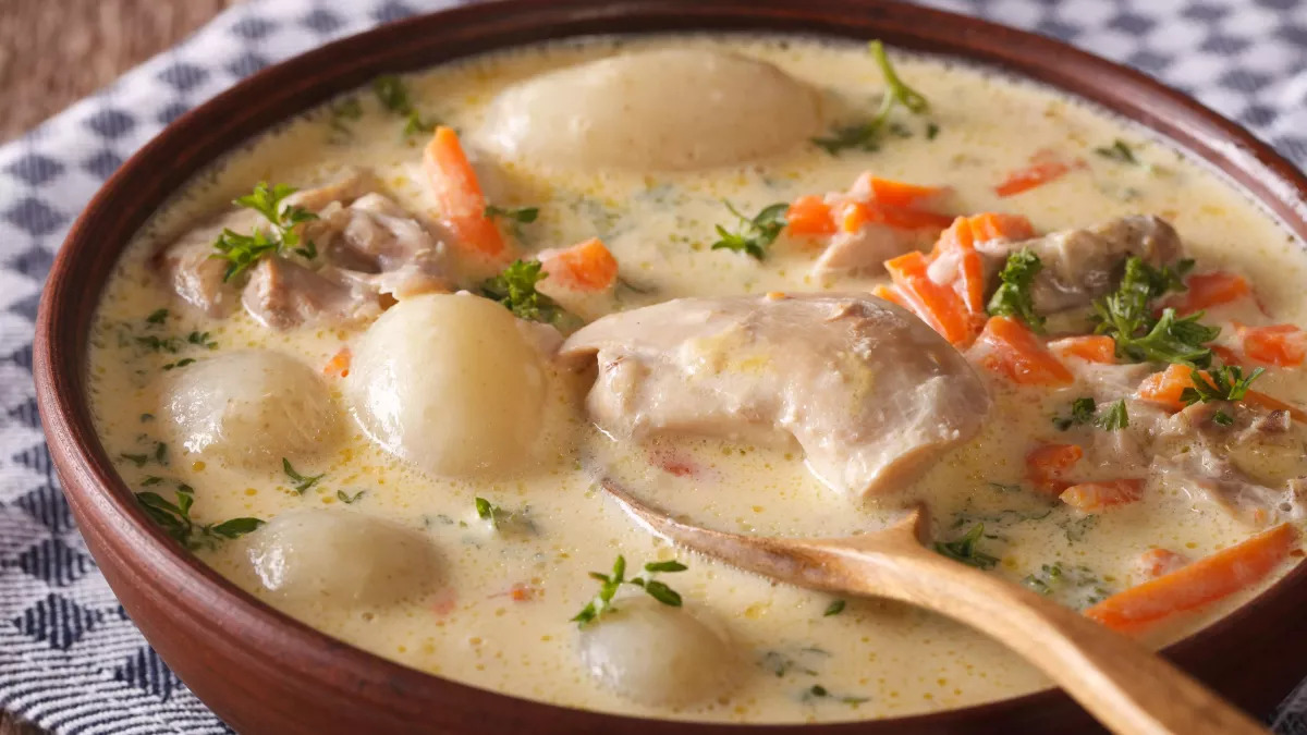 Waterzooi, a creamy Belgian stew, typically features chicken or fish simmered with vegetables like carrots, leeks, and potatoes in a rich broth, showcasing the country's comforting and flavorful culinary traditions.