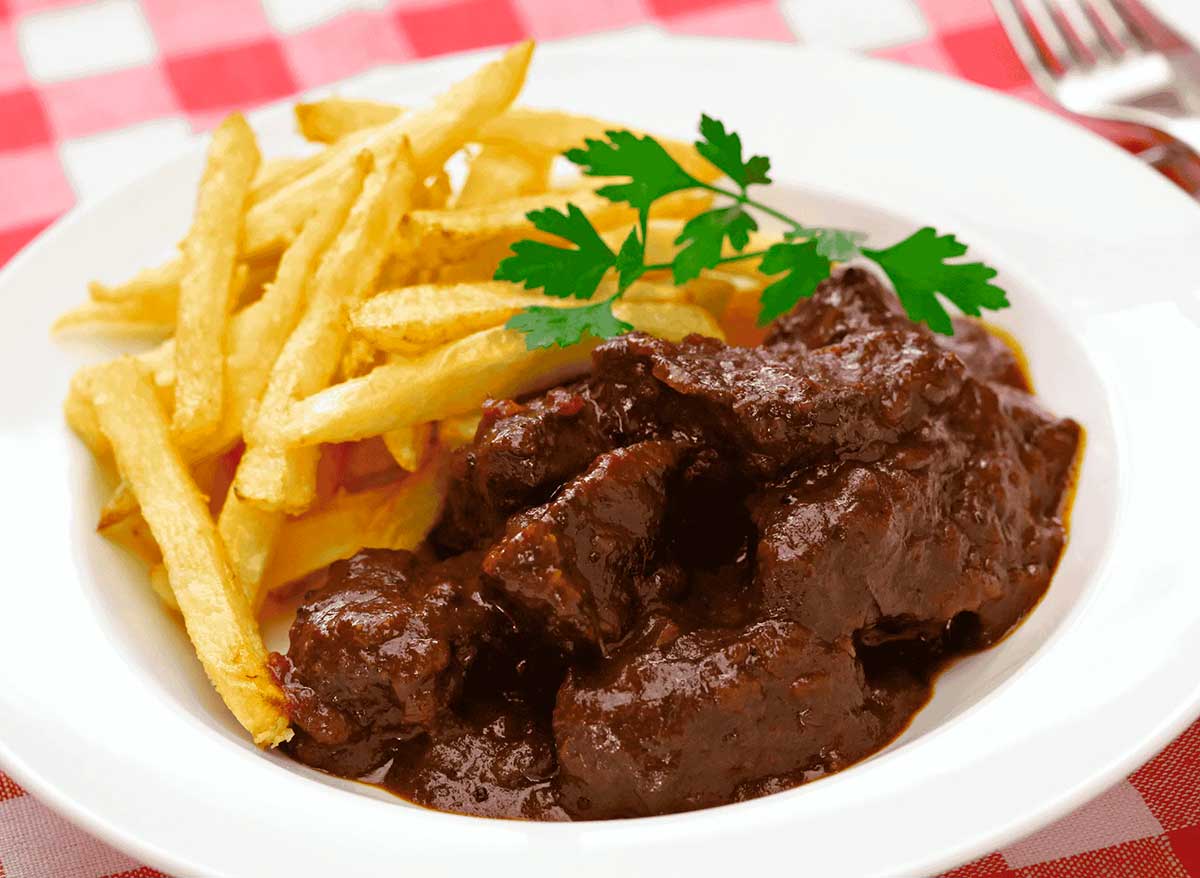 Stoofvlees, a classic Belgian beef stew, features tender chunks of beef slow-cooked in a rich, dark beer-based sauce, often served with fries or bread, representing the country's hearty and flavorful comfort food.