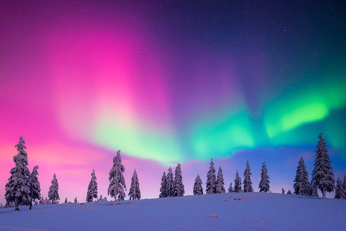 The Northern Lights, or Aurora Borealis, dance across the Finnish Lapland sky, displaying vibrant hues of green, pink, and purple, creating a breathtaking natural phenomenon against the backdrop of snow-covered landscapes and starry nights.