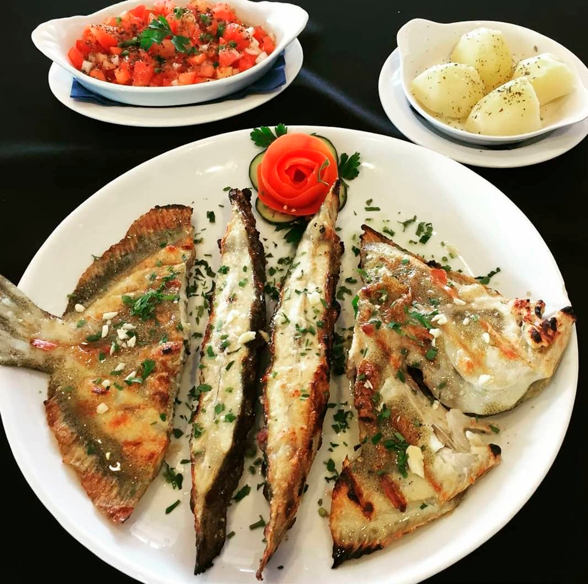Plates of traditional Portuguese food at Restaurante O Capelo, emphasizing the restaurant's commitment to local ingredients and classic recipes.