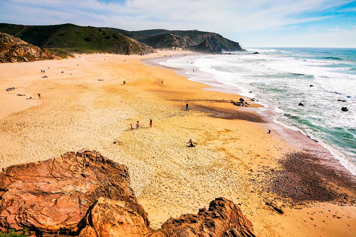 Praia do Amado, a renowned surf spot on Portugal's Vicentina Coast, boasts golden sands, powerful waves, and a laid-back atmosphere, attracting surfers and beachgoers alike.