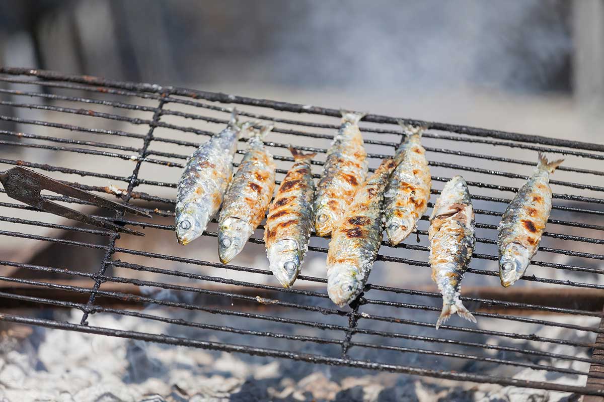 Algarvian grilled sardines, a quintessential summer dish, feature fresh, plump sardines seasoned with sea salt and grilled over charcoal, imparting a smoky flavor and crispy skin, often served with boiled potatoes and a simple salad.
