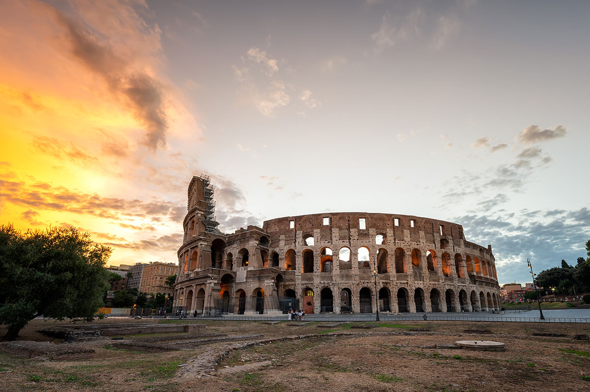 The Colosseum in Rome, Italy, bathed in the soft light of sunrise, reveals its ancient stone arches and weathered facade, creating a majestic and historic scene of the iconic Roman amphitheater.