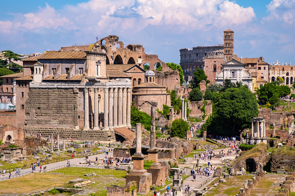 A group of tourists, guided through the Roman Forum, explores the ancient ruins, listening to historical insights amidst the weathered columns and archaeological remains, experiencing Rome's rich history firsthand.