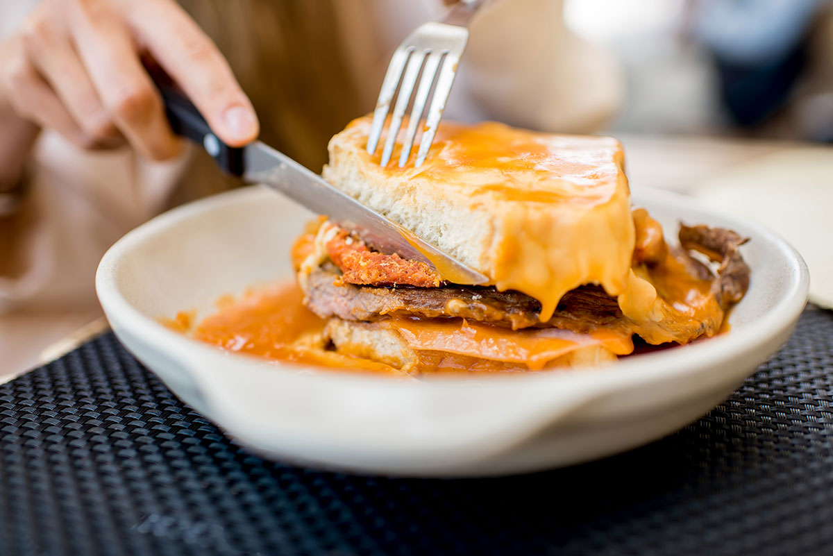 The Francesinha, Porto's iconic culinary masterpiece, is a decadent, multi-layered sandwich featuring various meats, smothered in a rich, spicy beer sauce, and often topped with a fried egg, representing the heart of traditional Portuguese comfort food.
