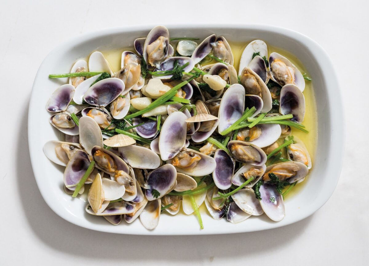 "Conquilhas à Algarvia," a beloved Algarve dish, features fresh wedge clams ("conquilhas") sautéed with garlic, olive oil, and coriander, showcasing the simplicity and freshness of the region's seafood and traditional flavors.