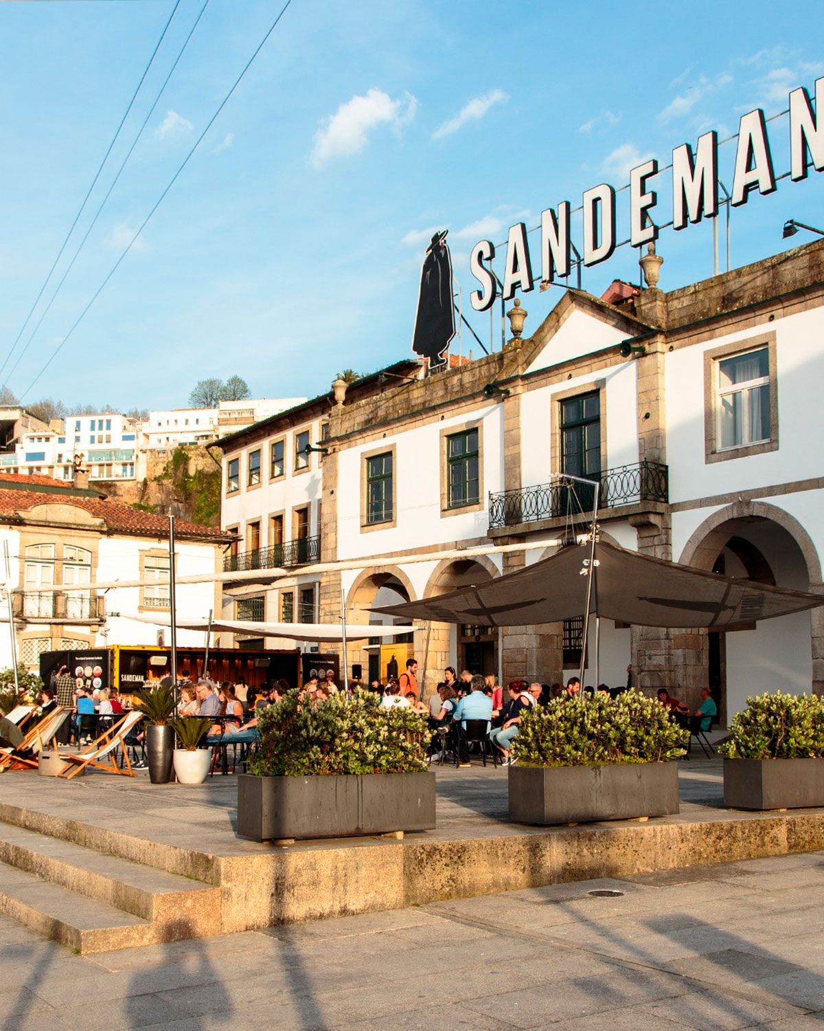 Sandeman Port cellars in Porto, Portugal, display their iconic black-caped Don figure, showcasing aged Port wine barrels and offering tours and tastings within a historic riverside setting.