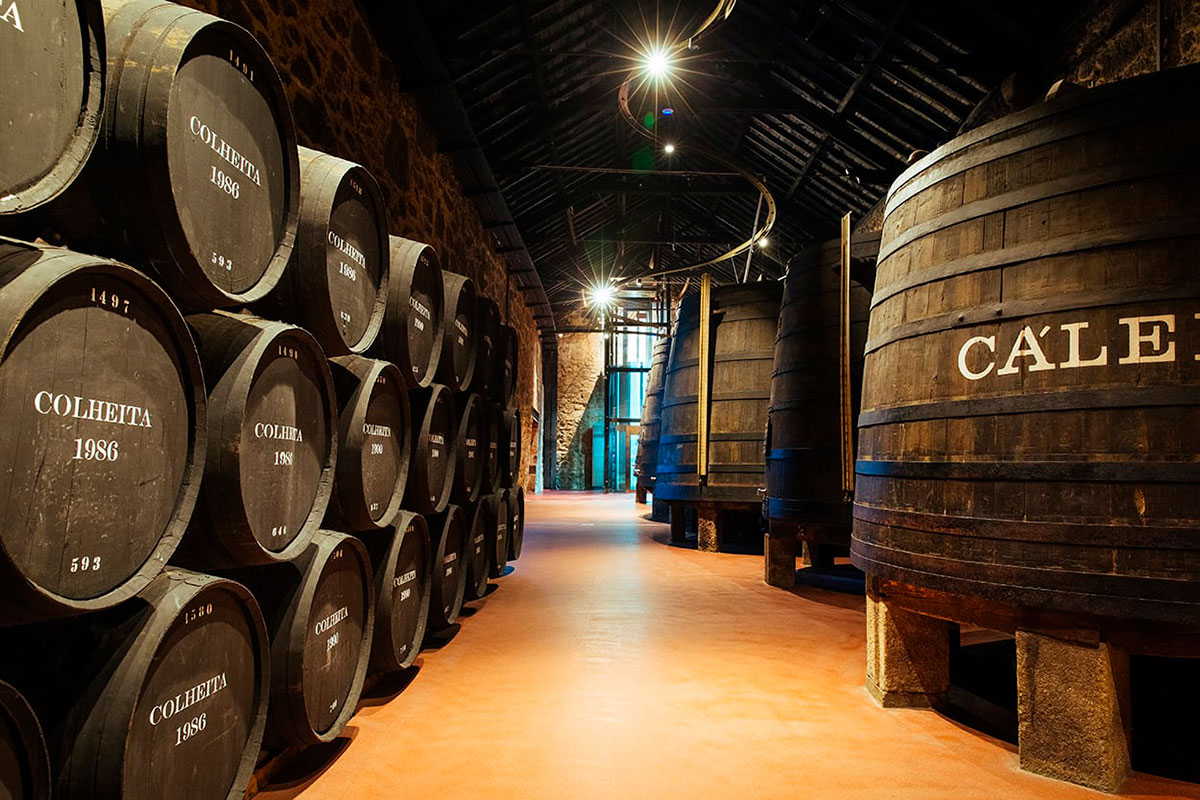 Caves Calém in Vila Nova de Gaia, Portugal, display rows of aged Port wine barrels within their historic cellars, offering tours and tastings with views of the Douro River and showcasing the tradition of Port wine production.