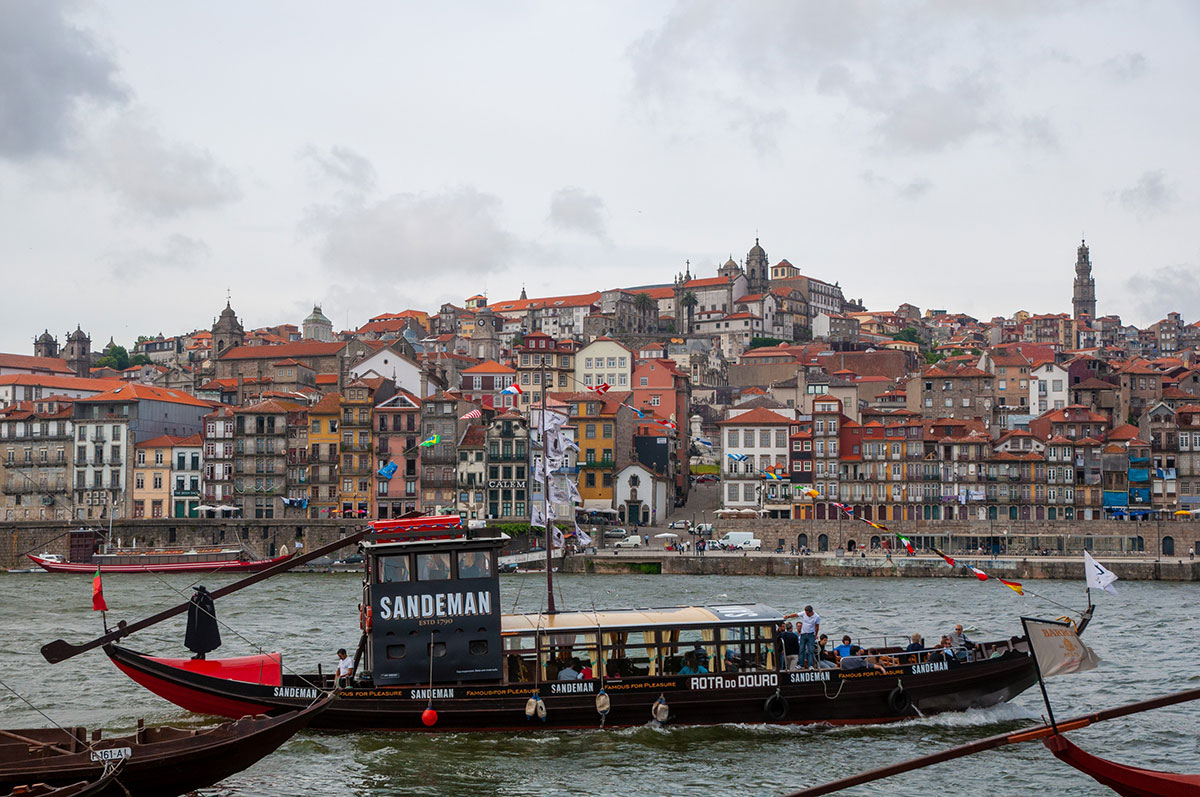 The Ribeira District in Porto, Portugal, features colorful, historic buildings lining the Douro River, cobblestone streets, and lively cafes, showcasing a UNESCO World Heritage site with vibrant waterfront views and traditional charm.