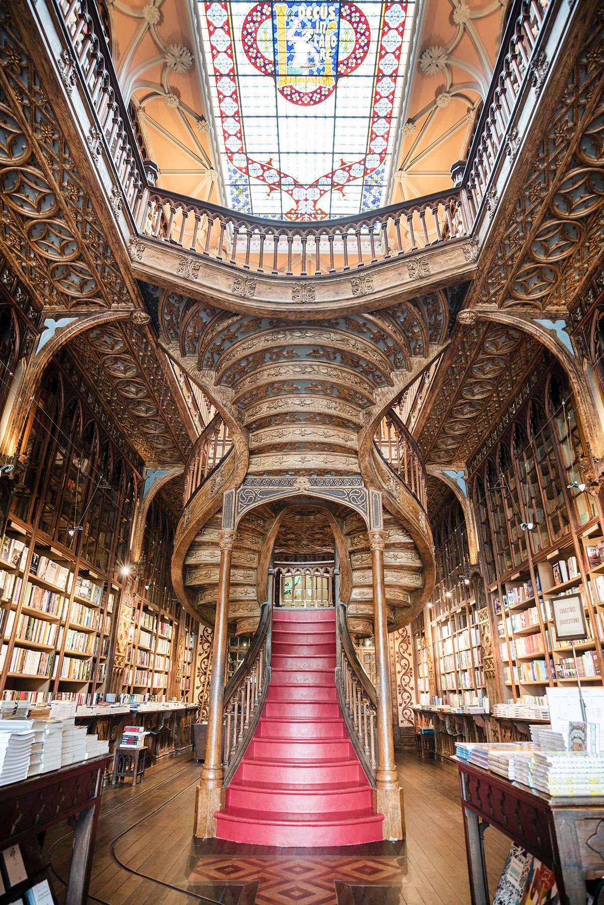 Livraria Lello in Porto, Portugal, features a stunning Art Nouveau interior with a grand red staircase, stained glass windows, and ornate bookshelves, creating a magical and historic bookstore experience.