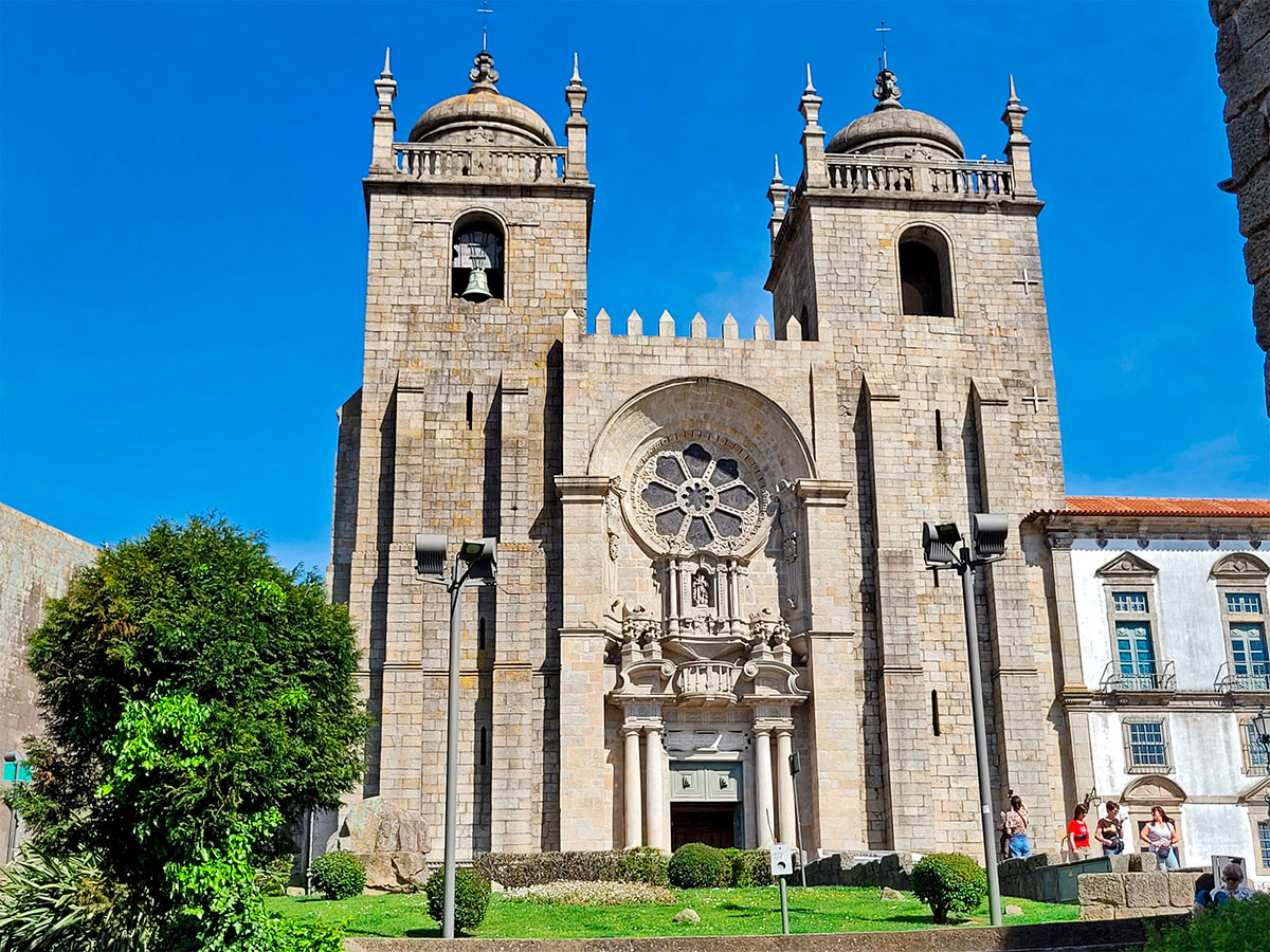 Porto Cathedral (Sé do Porto) features a Romanesque fortress-like facade, a Gothic rose window, and Baroque interiors with azulejo tiles, showcasing a blend of architectural styles and offering panoramic city views from its hilltop location.