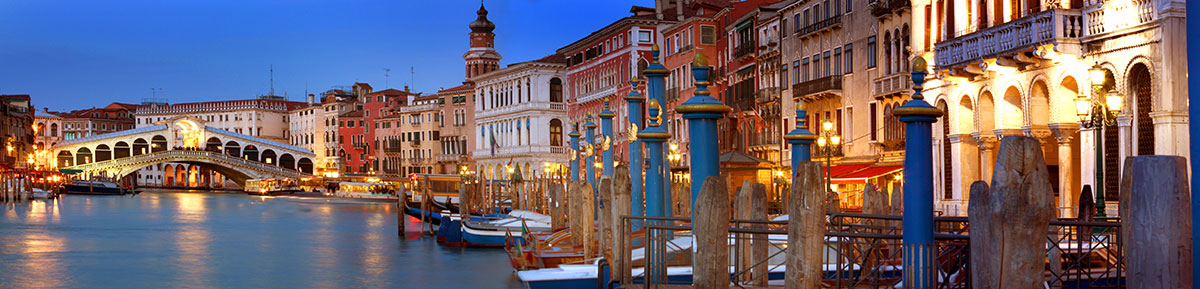 The Rialto Bridge in Venice, Italy, features a stone arch spanning the Grand Canal, lined with shops and bustling with gondolas and tourists, showcasing its iconic design and historical significance as a central landmark.