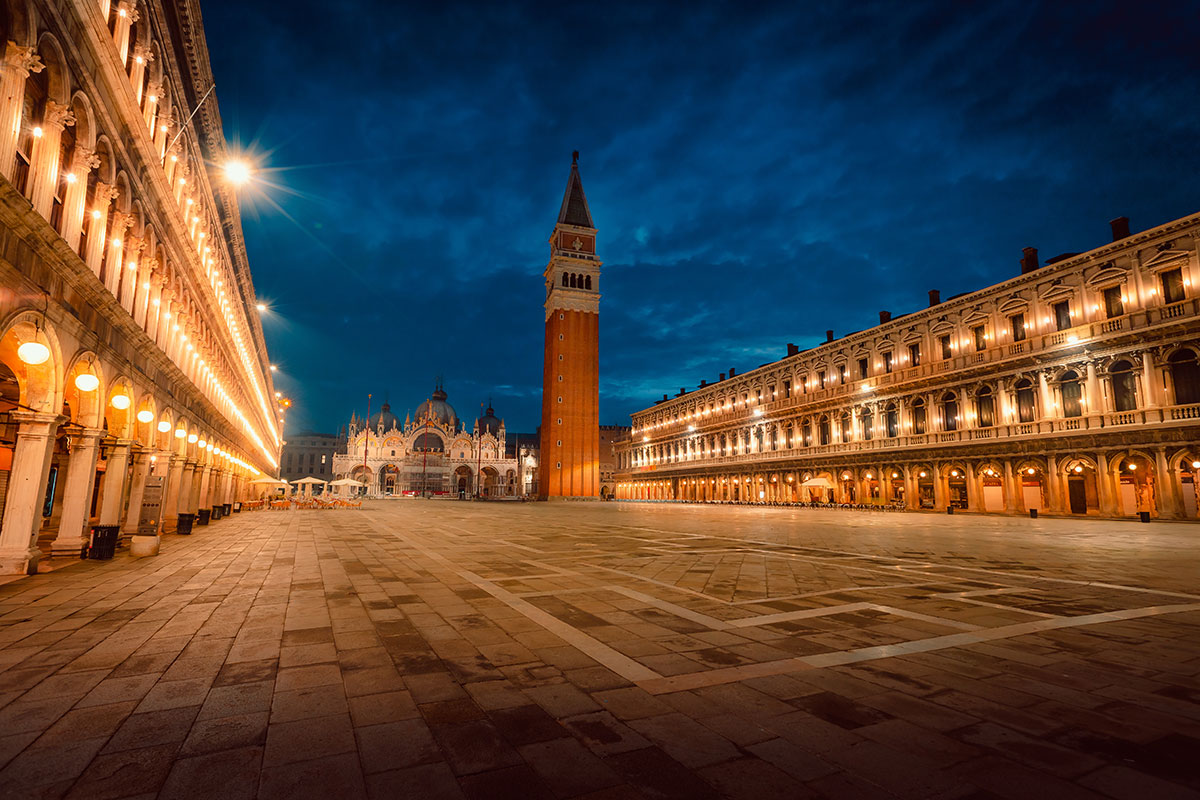 St. Mark's Square (Piazza San Marco) in Venice, Italy, features the iconic St. Mark's Basilica, Doge's Palace, and Campanile, surrounded by arcaded buildings and bustling with tourists, showcasing its historical architecture and vibrant atmosphere.