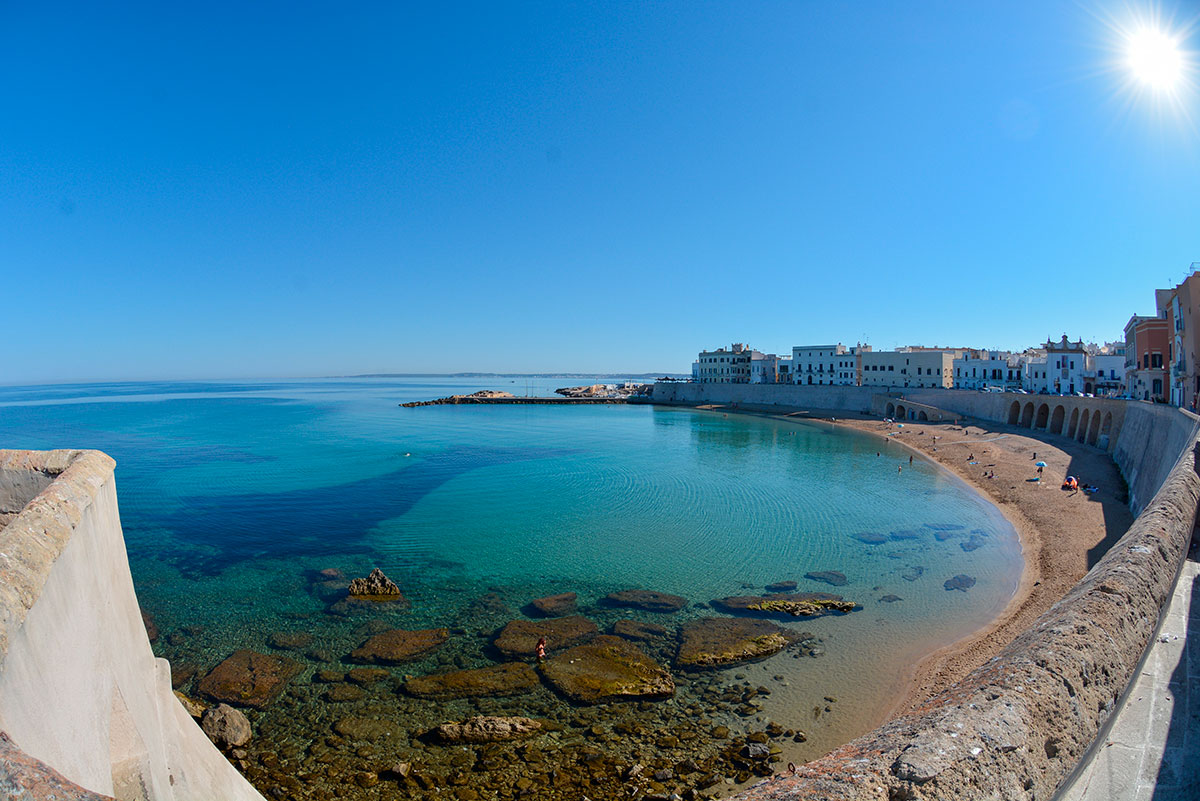 Gallipoli, Italy, features a historic island town connected by a bridge to the mainland, showcasing its ancient walls, Baroque churches, and sandy beaches along the Ionian Sea, blending historical architecture with coastal beauty.