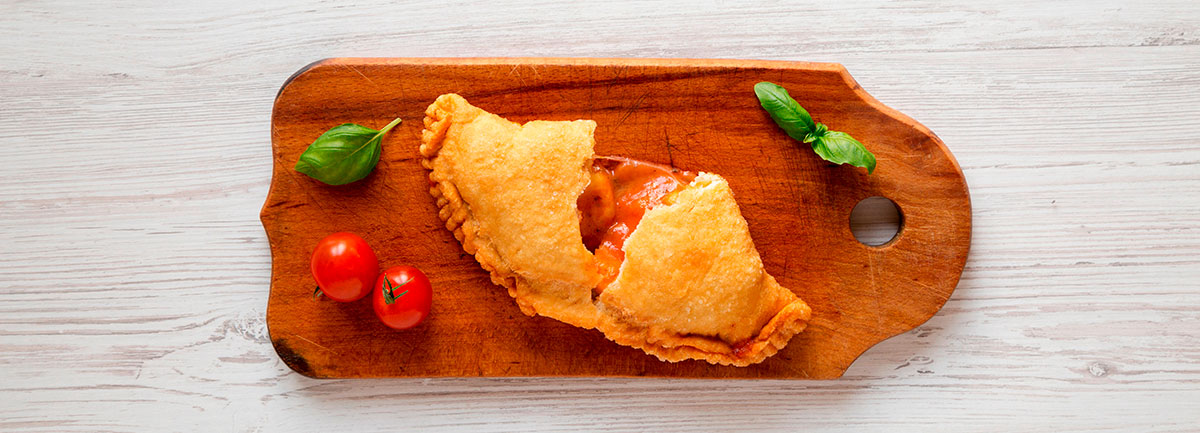 Homemade deep-fried Italian panzerotti calzone, golden brown and puffed, reveals a warm, cheesy filling, showcasing a traditional Italian street food snack.