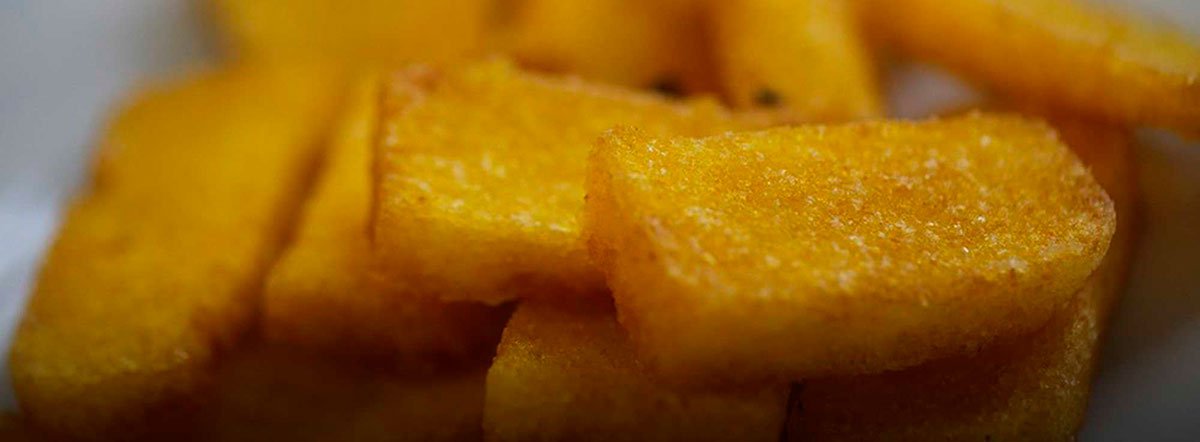 Sgagliozze from Bari, Italy, are golden-fried polenta pieces, served warm and crispy, showcasing a traditional street food snack of the Apulian region.