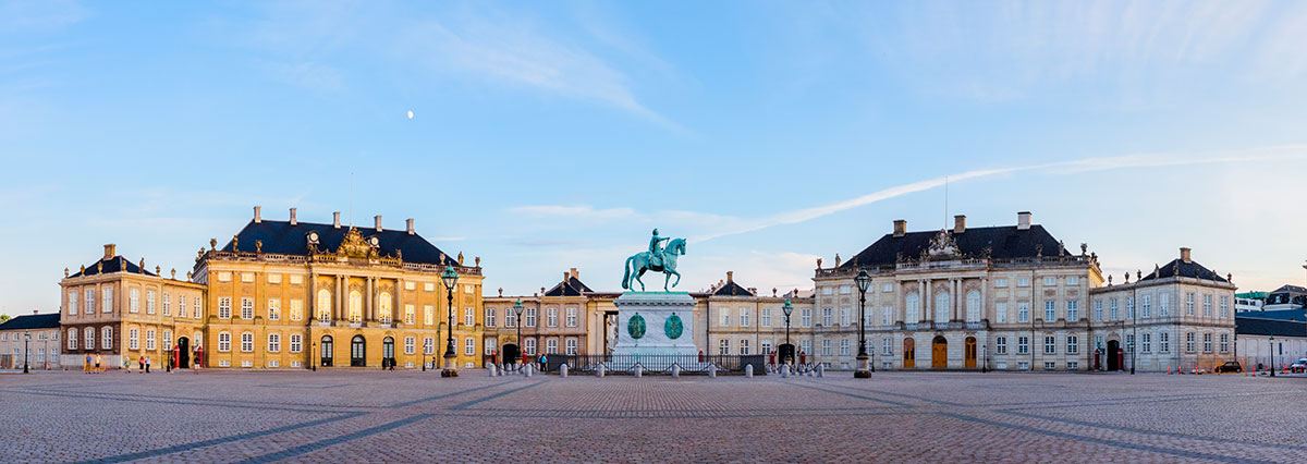 Amalienborg Palace in Copenhagen features four identical classical palace facades surrounding an octagonal courtyard, with the Royal Danish Guard standing watch, showcasing the royal residence's architectural grandeur and historical significance.