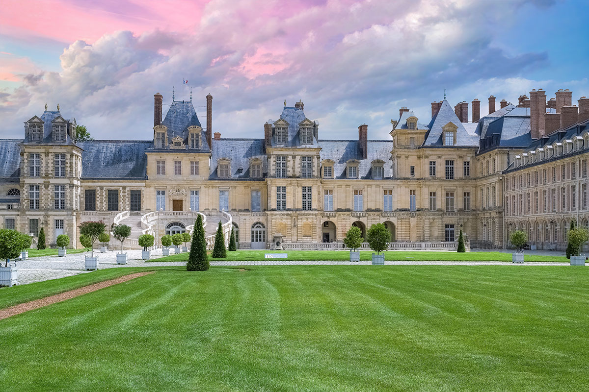 A grand, historic Chateau de Fontainebleau, featuring ornate architecture and expansive gardens, showcasing French royal history.
