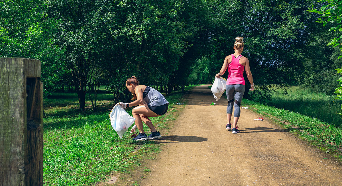 A traveler practicing Leave No Trace by picking up litter while hiking.