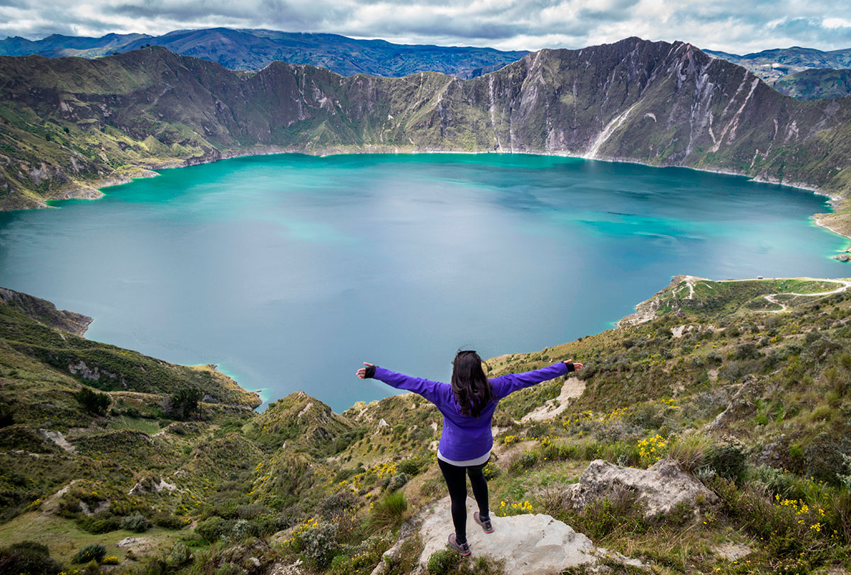 Solo traveler standing on a hilltop, overlooking a breathtaking landscape.