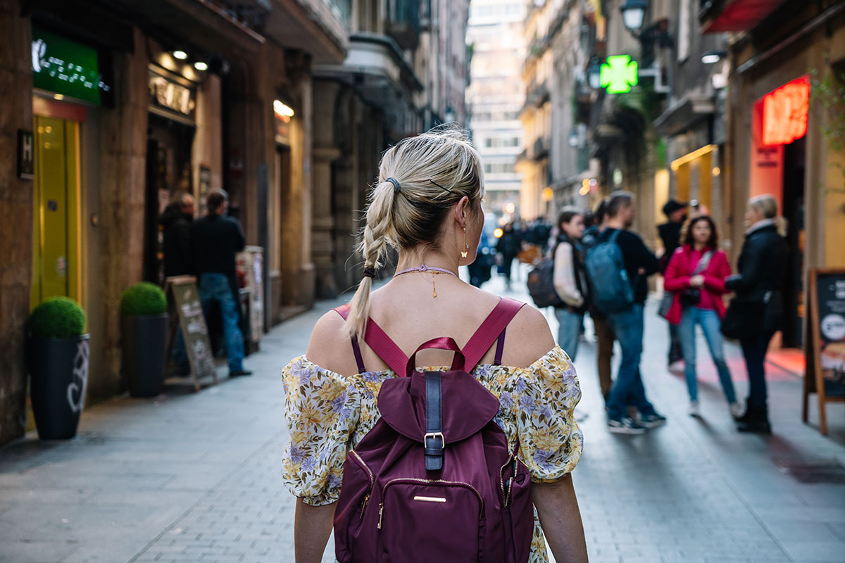 A solo traveler with a backpack walking through the colorful streets of a European city.
