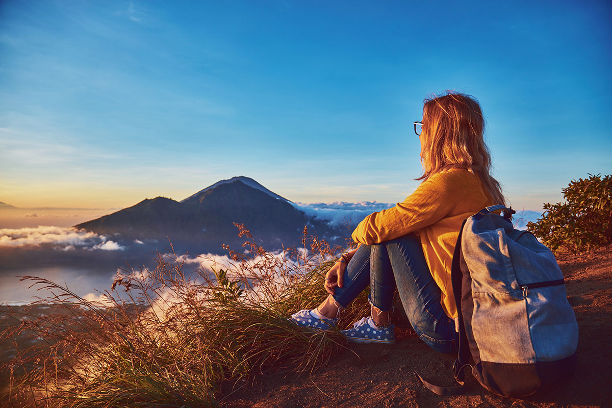 Woman enjoying nice landscape and sunrise from a top of mountain Batur, Bali, Indonesia