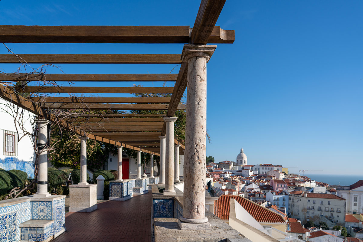 Miradouro das Portas do Sol in Lisbon, Portugal, offers panoramic views of the Alfama district's terracotta rooftops cascading down to the Tagus River, showcasing a classic Lisbon cityscape with historical charm.