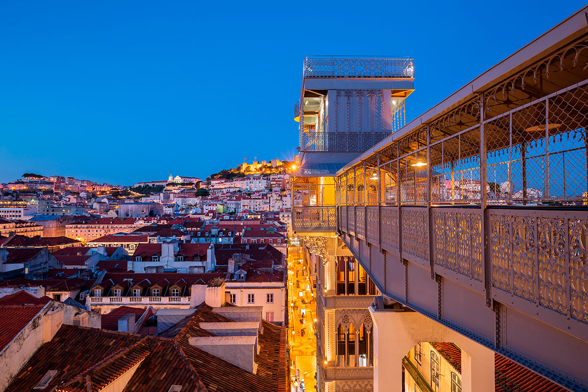 An ornate ironwork elevator, the Elevador de Santa Justa in Lisbon, Portugal, offers a unique viewpoint overlooking the Rossio Square and the cityscape, with blue skies visible above.