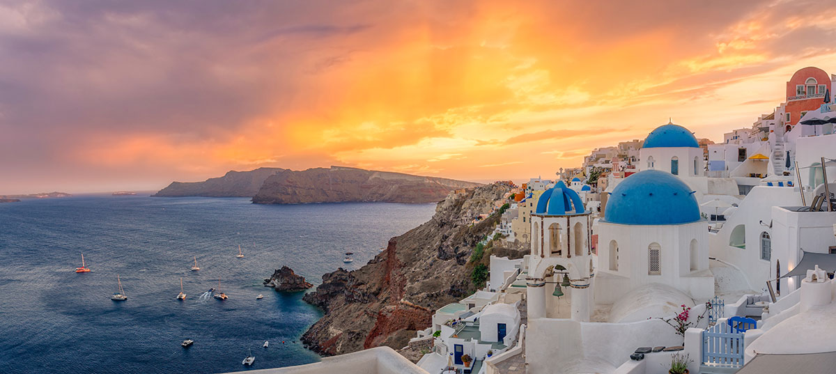 Santorini, Greece, featuring whitewashed houses and blue-domed churches during sunset.