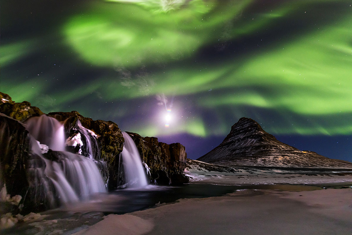 The Northern Lights over Iceland’s snowy landscapes, captured with long-exposure photography.