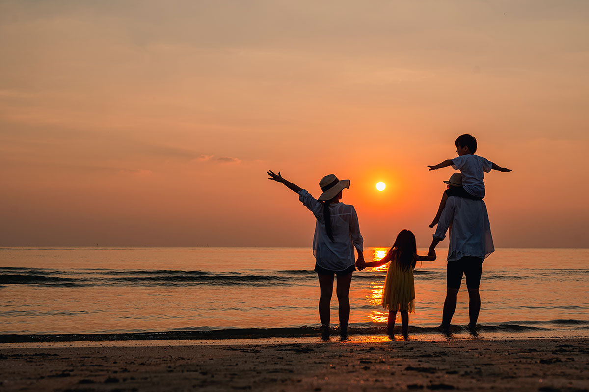 A family standing together on the beach, watching a beautiful sunset.
