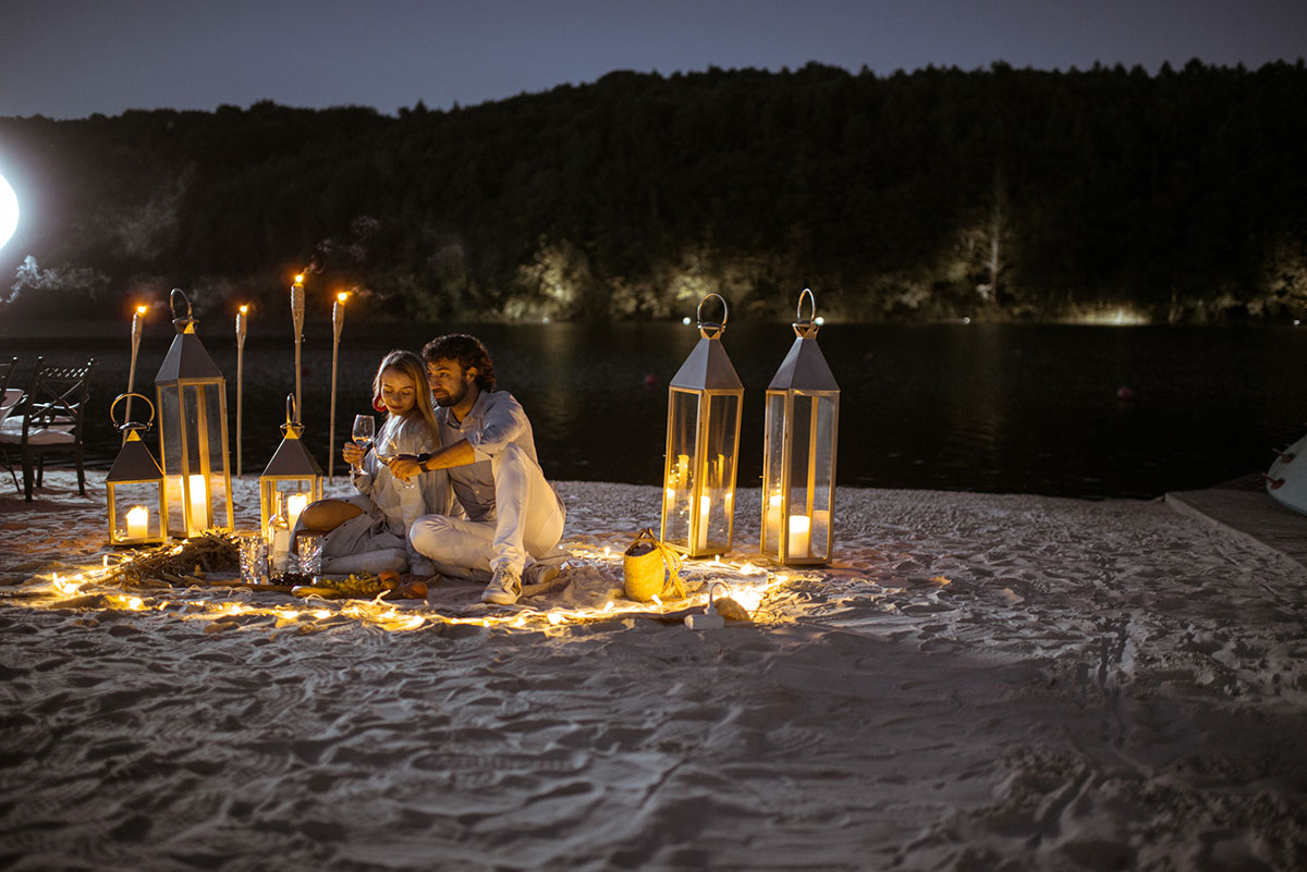 A candlelit dinner set up for two on a beach in Portugal, with ocean waves in the background.