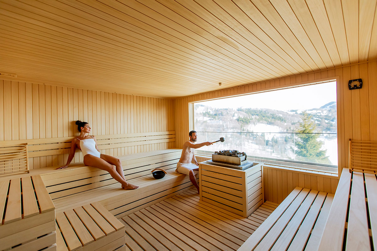 A modern Finnish sauna building by the sea with steam rising from its wooden deck.