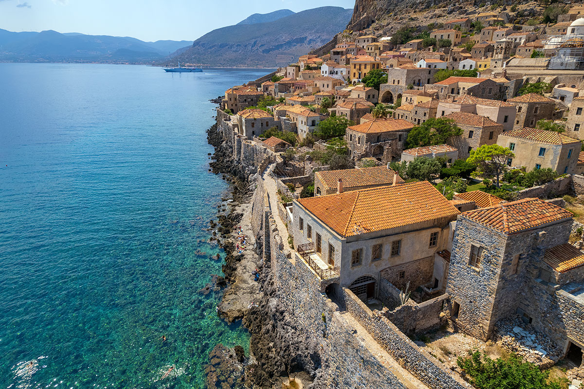 A scenic Greek village in Peloponnese with stone houses and a mountain backdrop.