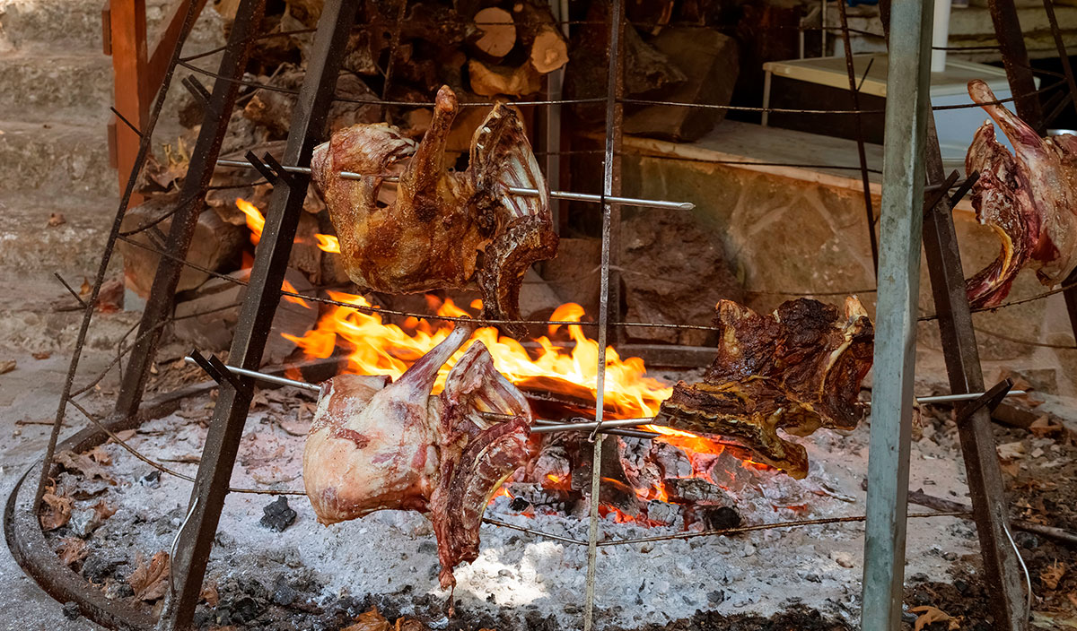 Traditional Cretan lamb roasting on an open fire in a rustic setting.