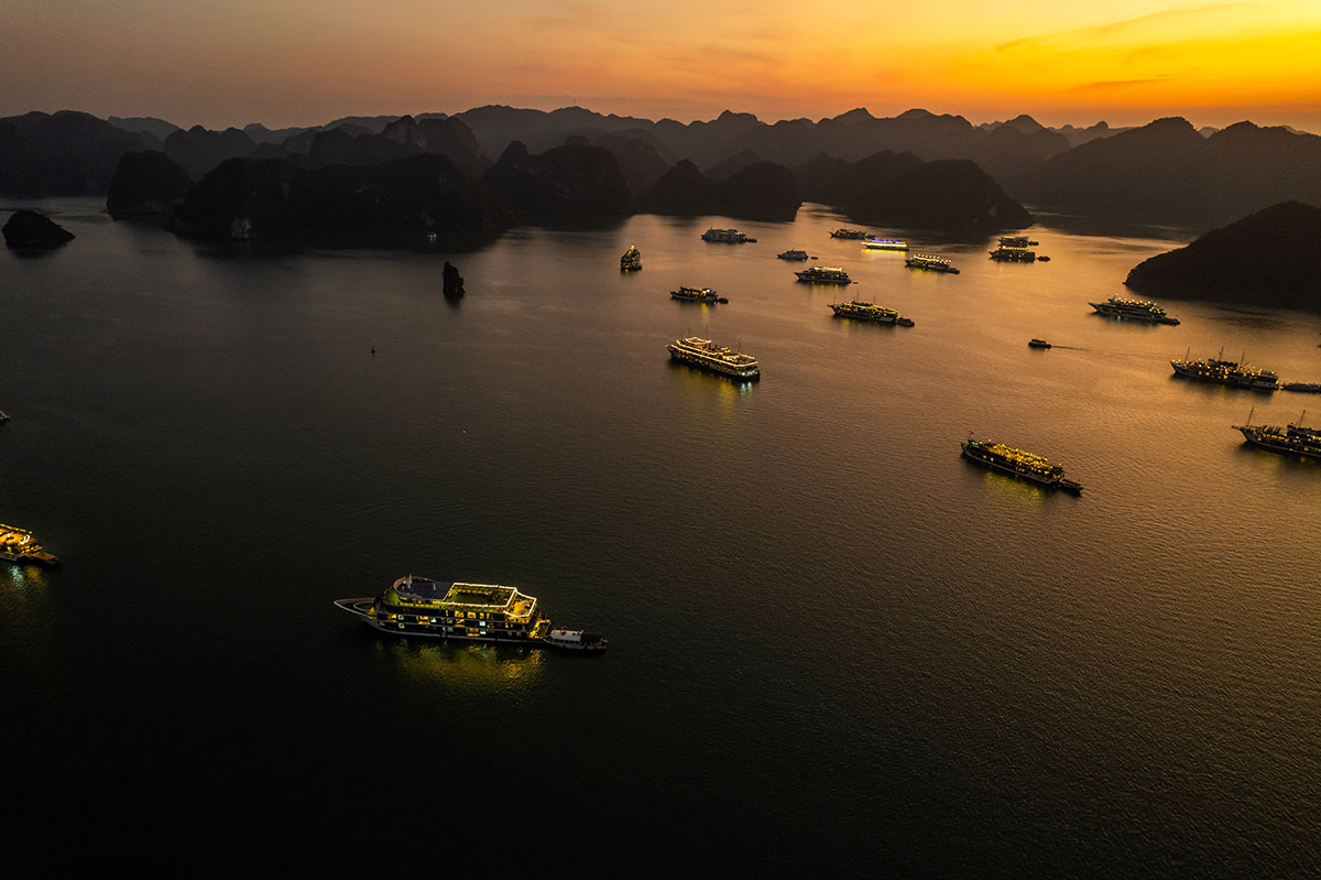 Golden sunset over Hạ Long Bay, illuminating luxury cruise ships against the backdrop of limestone karsts.
