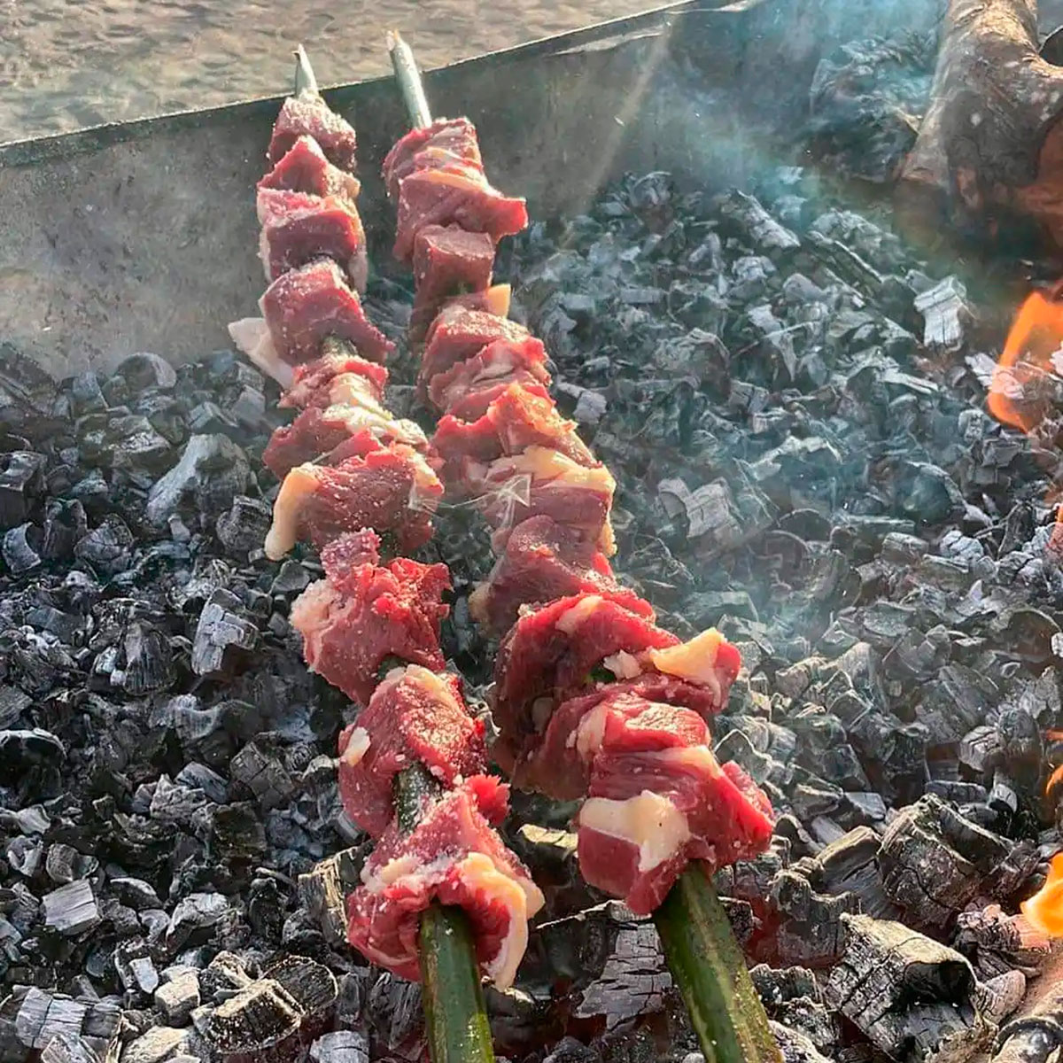 Beef espetada grilling on bay laurel skewers over an open flame