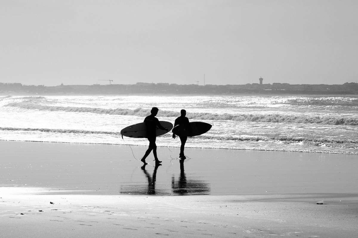 Surfer walking on Baleal beach with waves in the background