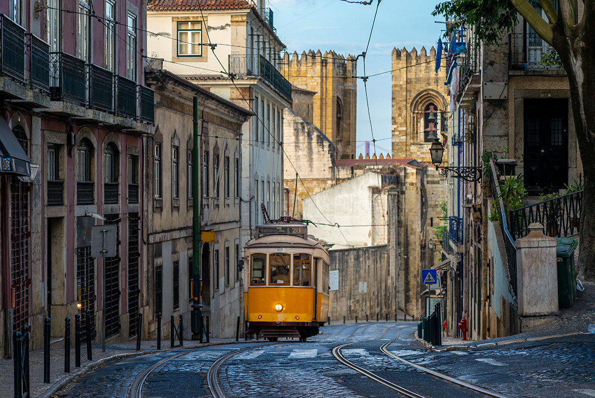 Vintage yellow Tram 28 passing through a Lisbon street