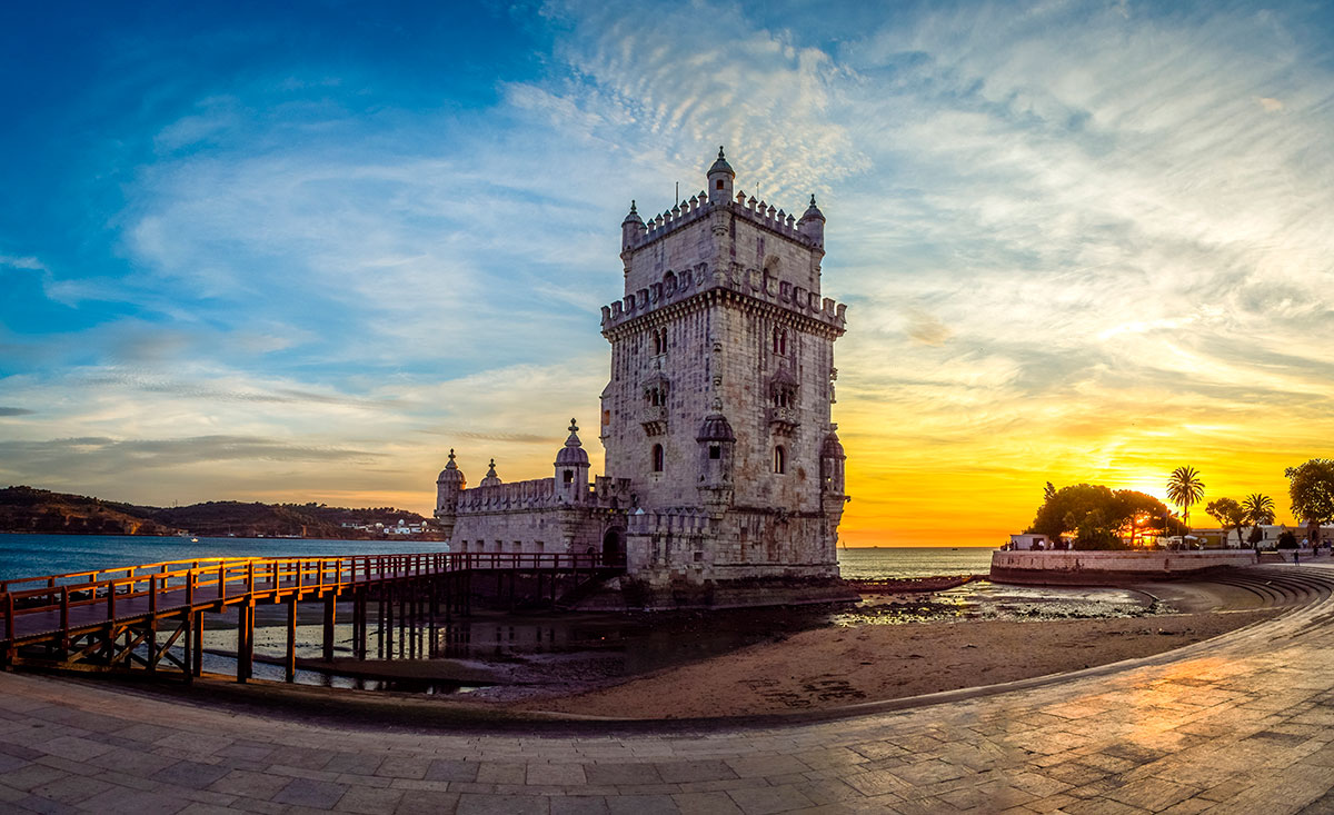 Exterior view of Belém Tower near the water at sunset