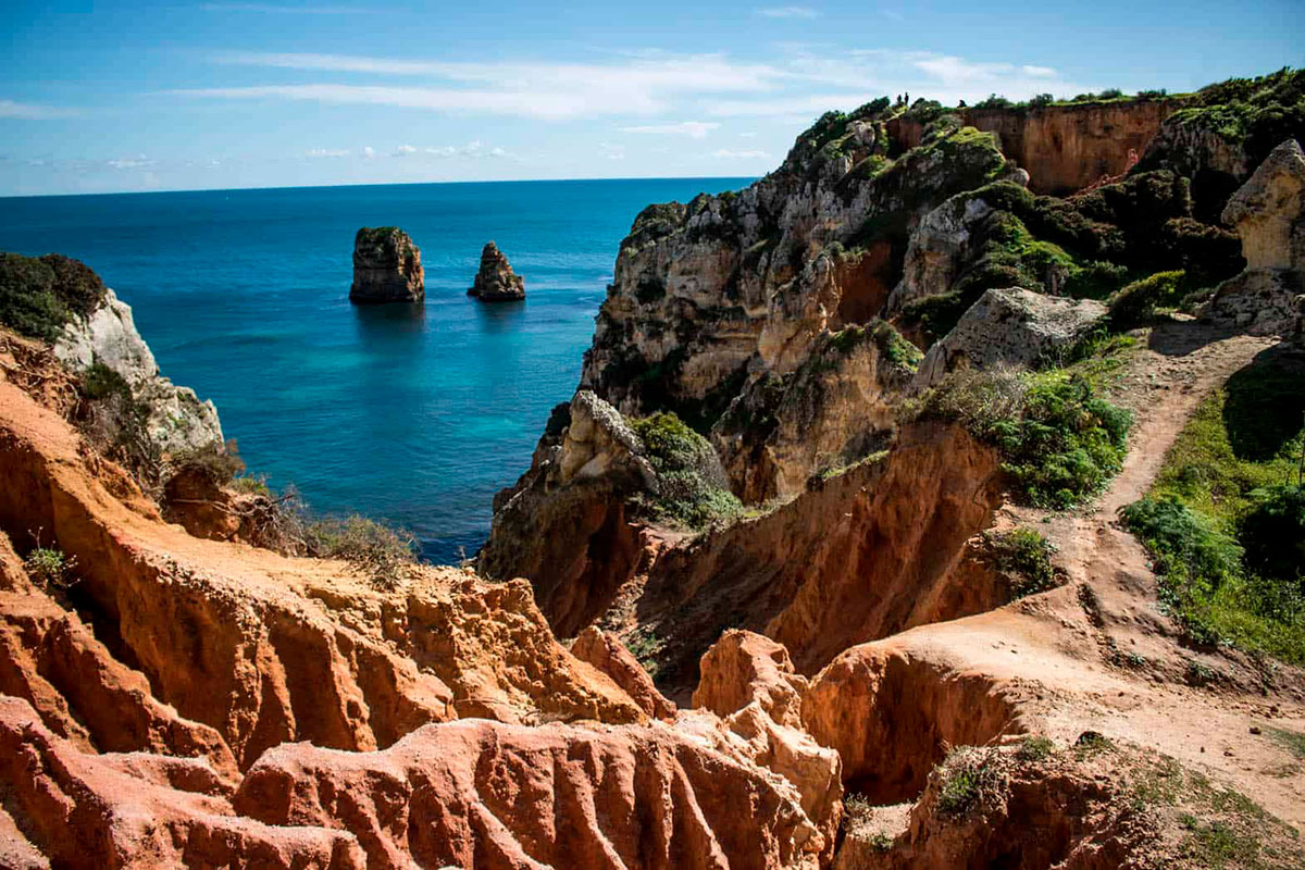 Hiker walking along the scenic cliffs of the Seven Hanging Valleys Trail in the Algarve.