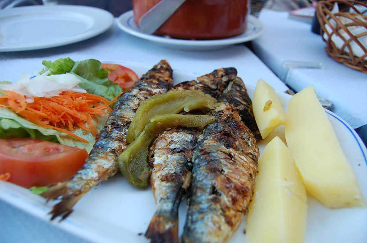 Plate of freshly grilled sardines served with lemon and herbs